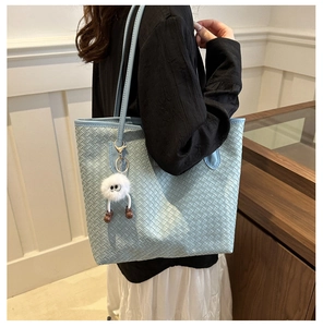 Détail du sac cabas tissé bleu clair avec un charmant pendentif monstre blanc
