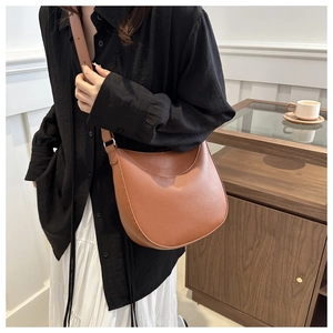 Detailed texture of caramel brown crescent shoulder bag with silver buckle and pebbled leather
