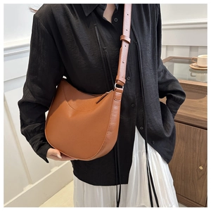Close-up of brown crescent shoulder bag with lychee grain texture on a model
