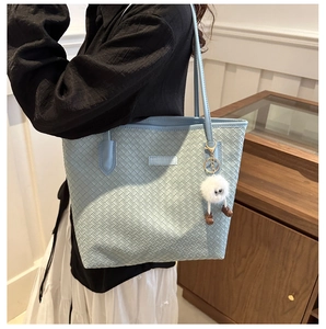 Détail du sac cabas tressé bleu clair avec étiquette FASHION & BAGS et breloque peluche