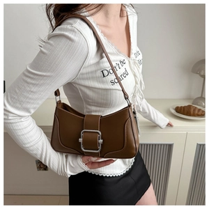 Sac sous le bras en cuir marron avec boucle argentée porté à l'épaule du mannequin