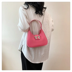 Detail of pink crescent bag with silver bow accent and versatile metal chain strap