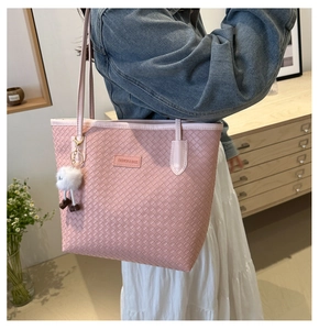 Détail du sac cabas rose tressé avec un pendentif décoratif en forme de pompon blanc