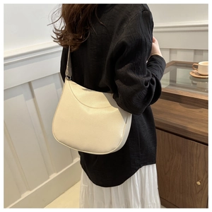Off-white lychee texture leather hobo bag worn as a shoulder bag on a female model
