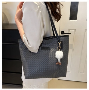 Détail du grand sac cabas gris matelassé avec un charm en peluche et logo gravé