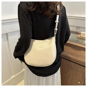 Detail of off-white lychee grain leather hobo bag with adjustable shoulder strap on model