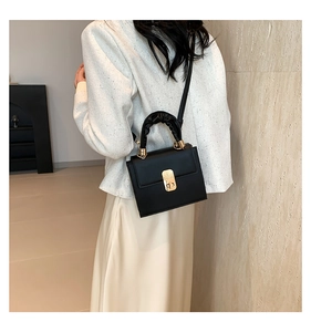 Detail of black faux leather mini square bag with pleated handle and gold clasp