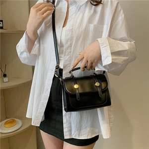 Classic black faux leather crossbody bag with gold hardware worn by a model
