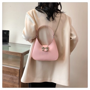 Detailed shot of pink moon bag with silver bow buckle and chain strap on a model