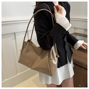 Macro detail of khaki tote bag featuring embossed logo text and stylish side drawstring
