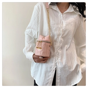 Détail du sac seau rose avec surpiqûres en cœur, décor nœud et chaîne dorée