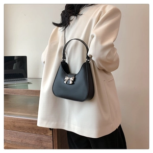 Detail of black crescent hobo bag with silver bow charm and dual strap options