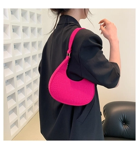 Detailed view of magenta crescent underarm bag with embossed crocodile leather texture
