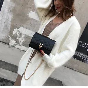 Detailed view of black quilted chain bag with gold hardware worn by a model