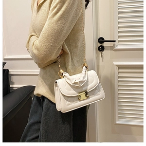 Detail of off-white quilted crossbody bag with gold twist lock and fabric handle decoration