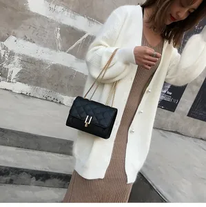 Detail shot of black quilted chain bag with gold metal lock and elegant stitching texture