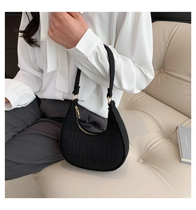 Detailed view of black crocodile pattern faux leather handbag with golden metal hardware