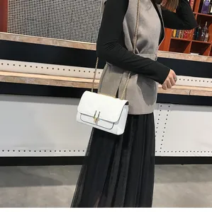 White quilted crossbody bag with gold chain strap shown on model in studio