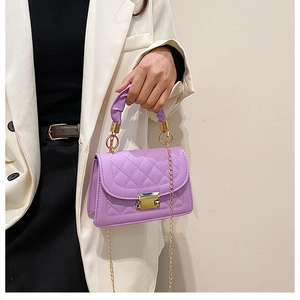 Close-up of purple quilted square bag featuring gold twist lock and chain strap detail
