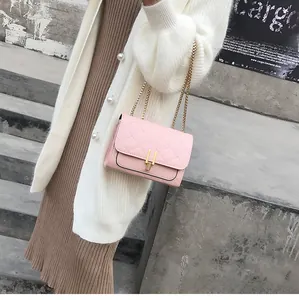 Pink quilted crossbody bag with gold chain strap worn with a white knit cardigan