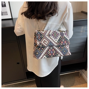 Detail of colorful geometric woven tote bag with metallic chain strap and flap closure