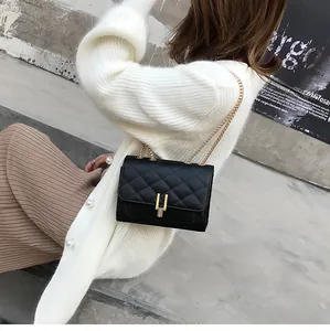 Close-up of black quilted shoulder bag featuring gold chain and U-shaped metal buckle