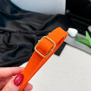 Macro detail of adjustable orange felt shoulder strap with golden metal buckle