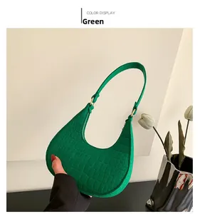 Detail of green hobo bag with crocodile embossed texture and golden metal hardware