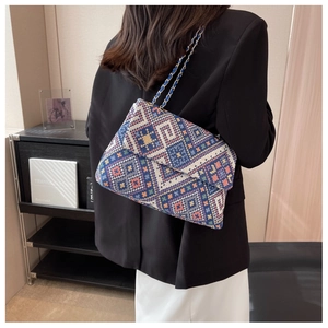 Detailed back view of a woman wearing a colorful geometric woven crossbody bag with chain