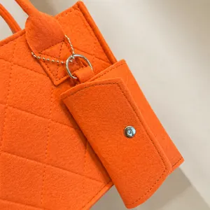 Detail of orange quilted felt tote bag featuring matching pouch and metal chain