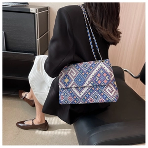 Detail of geometric woven patterns and gold chain strap on ethnic style shoulder bag