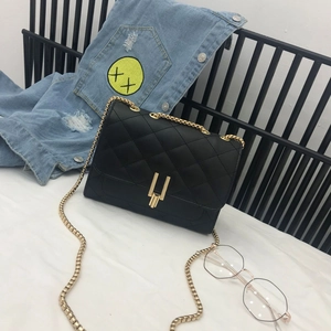 Detail of black quilted chain bag featuring a gold irregular metal lock and leather texture