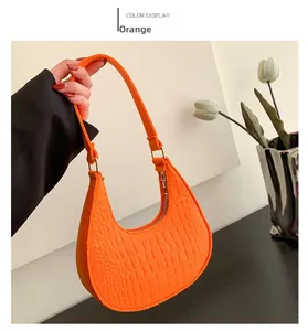 Detail of vibrant orange embossed crocodile pattern on crescent shoulder bag