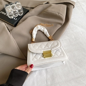 Detail of white quilted handbag with golden lock and ruched fabric handle texture