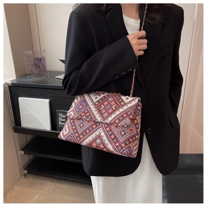 Detail of woven handbag with colorful geometric diamond pattern and gold chain strap