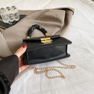 Detail of black quilted leather handbag with gold clasp and elegant pleated handle