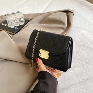 Detail of black quilted leather shoulder bag featuring gold clasp and chain strap