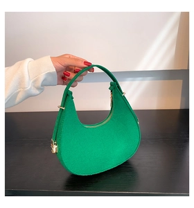 Detail of green felt crescent hobo bag with golden hardware and adjustable top handle