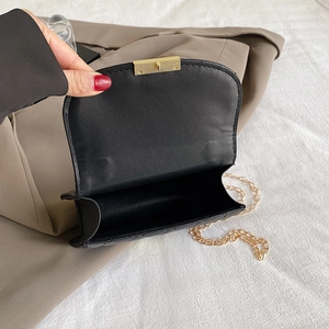 Detailed interior view of a black quilted crossbody bag with a gold metal turn-lock