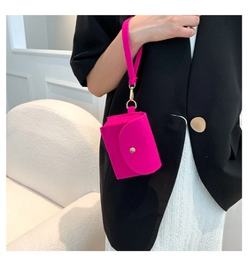 Close-up of fuchsia felt clutch bag with golden snap button and matching wrist strap