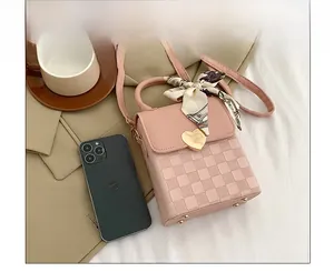 Pink mini crossbody bag with gold heart lock and printed scarf, shown next to a smartphone