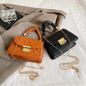 Detail of quilted leather flap bags with gold chain straps in orange and black tones