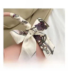 Close-up of pink leather handbag handle decorated with a floral printed silk scarf