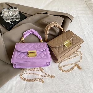Close-up of quilted handbag detailing elegant gold metallic lock and pleated cloud handle