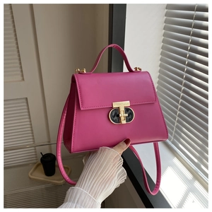 Detail showing bright pink leather handbag with gold T-shaped lock and sturdy handle