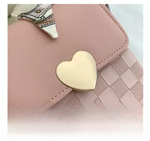Detail of pink PU leather crossbody bag with heart lock and silk scarf on handle