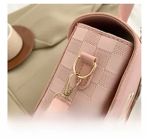 Close-up of pink checkered textured small square bag with elegant gold metal hook details