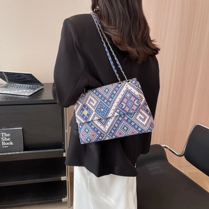 Ethnic style geometric knit shoulder bag with gold chain strap shown on a model