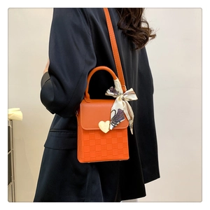 Detail of orange checkered leather crossbody bag with heart buckle and printed silk scarf