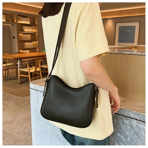 Sac à bandoulière chic en cuir noir minimaliste porté avec une tenue moderne